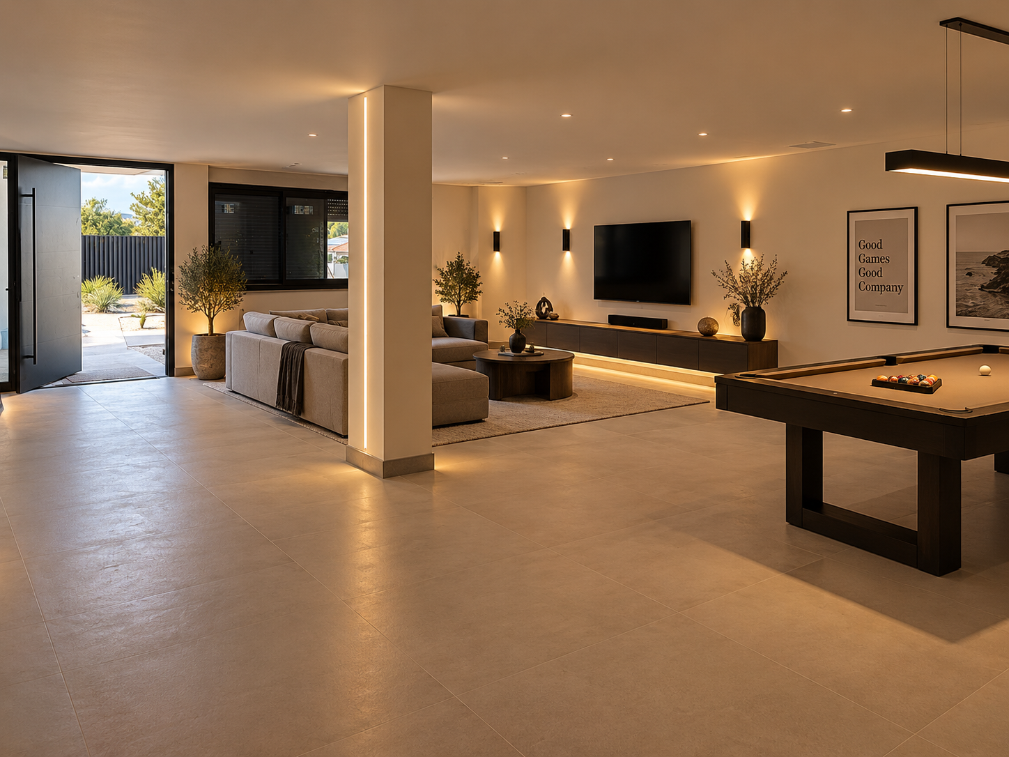 Lower leisure level — open-plan games and living area with a grey sectional sofa, round coffee table, and a tan-felt pool table beneath a linear pendant light